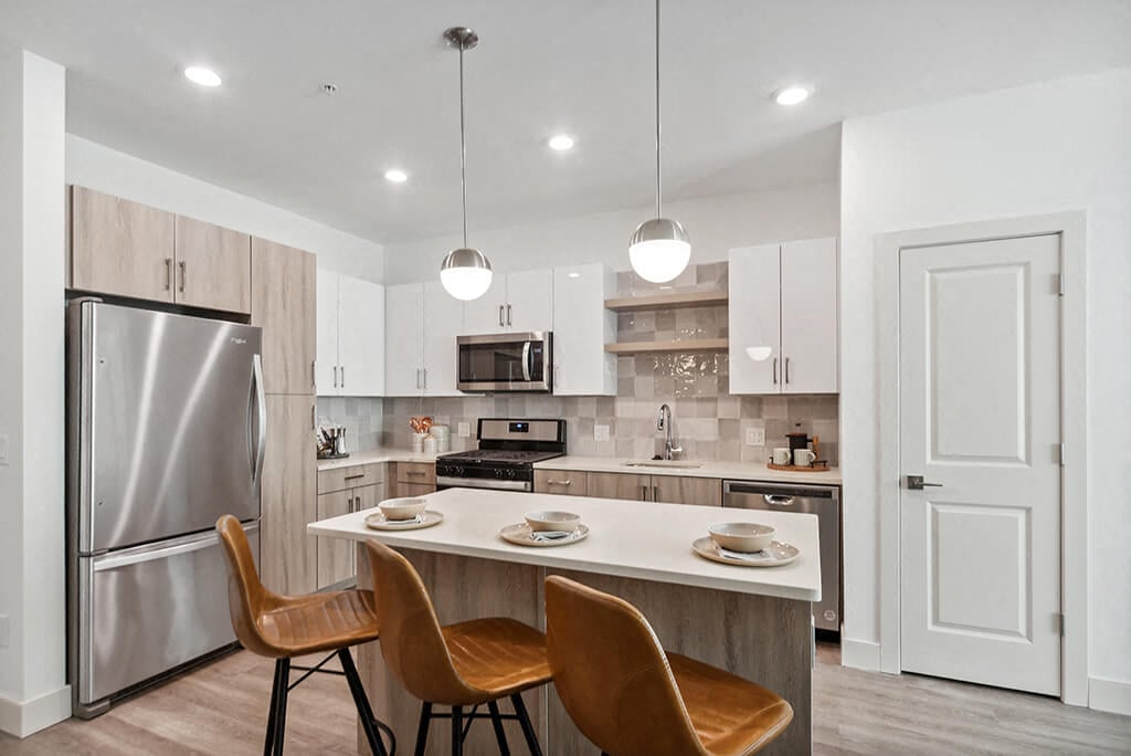A bright, modern kitchen with a kitchen island at The Quill Apartments in Milford, Massachusetts.